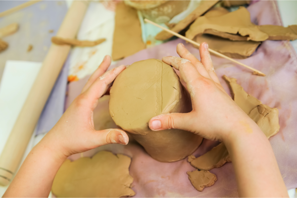 A child handling clay to make a ceramic mug