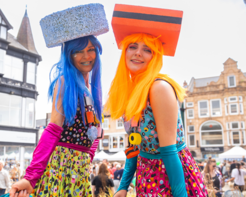 Two women in vibrant costumes performing at the Pontefract Liquorice Festival.